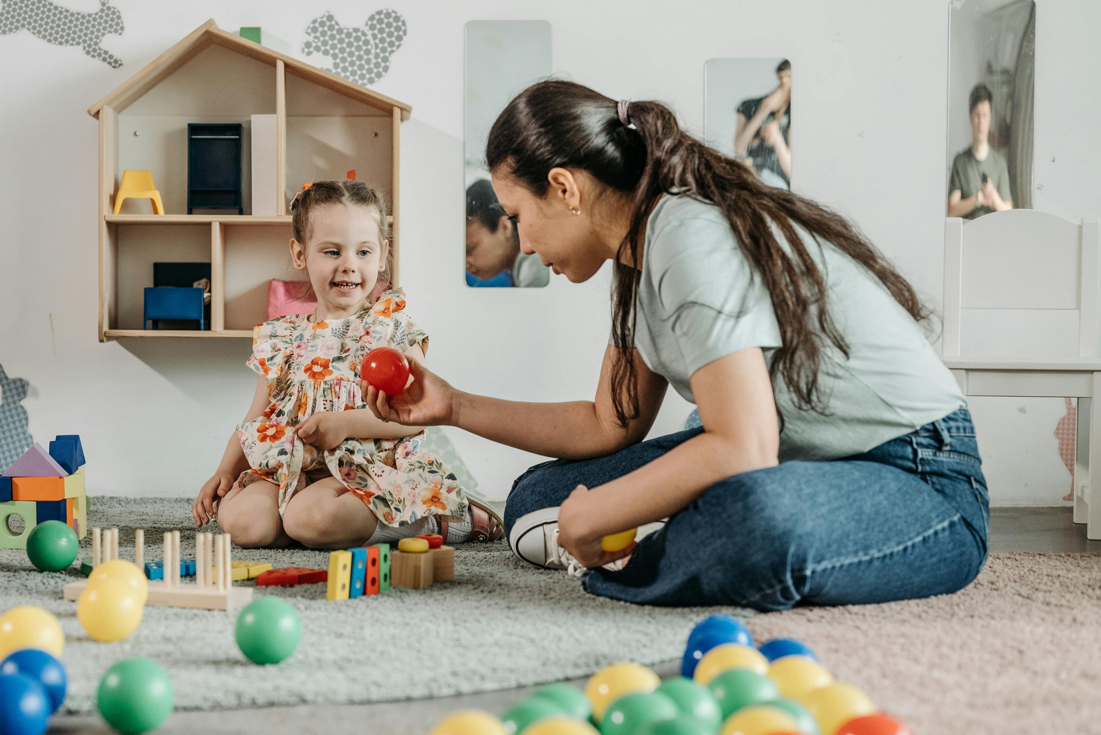 A therapist and child playing together on the floor with blocks and toys
