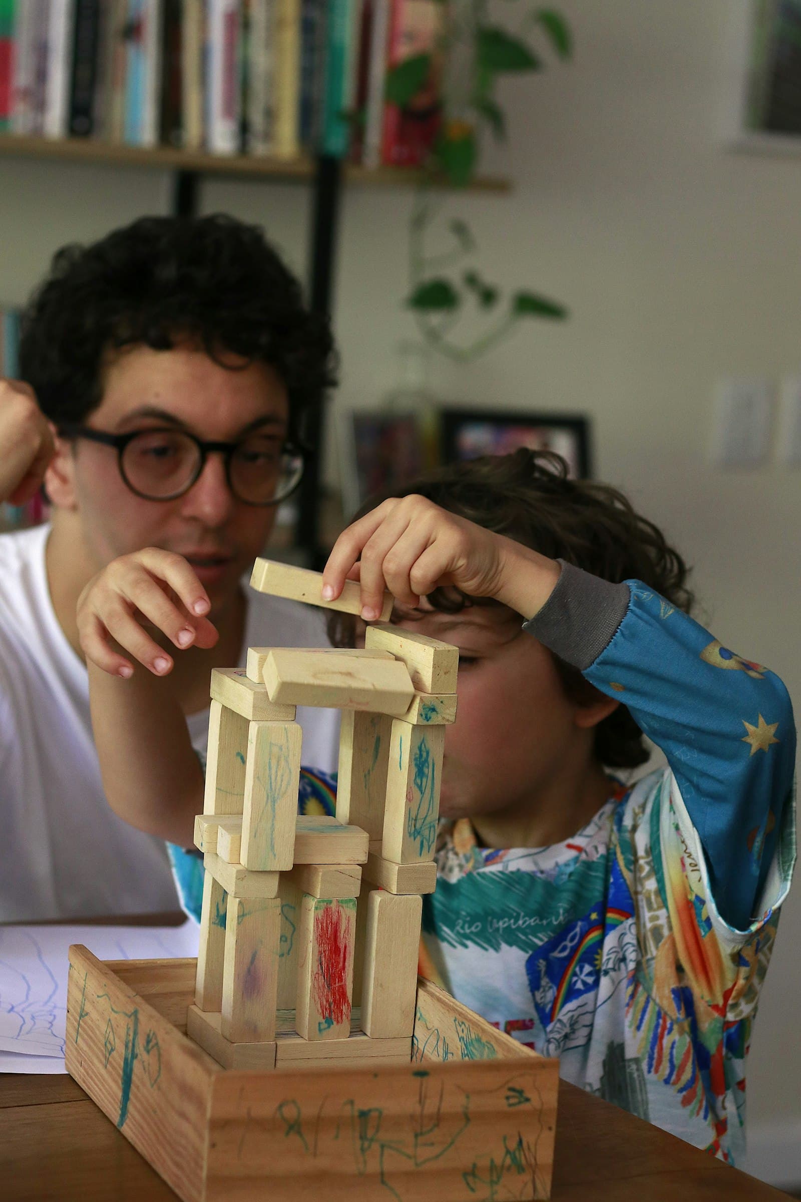 An adult and a child building together with wooden blocks